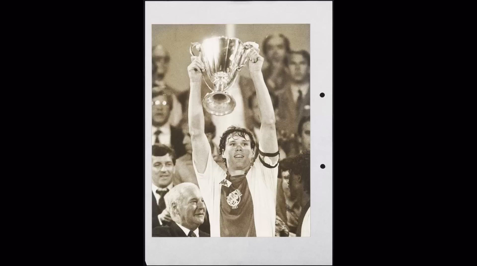 a black and white photo of a man holding a trophy