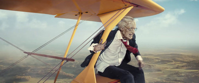 a man sitting on top of a yellow biplane