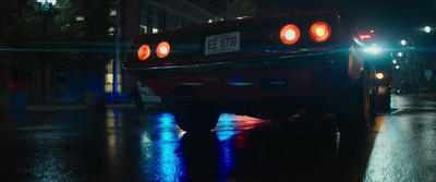 a red sports car parked on a wet street at night