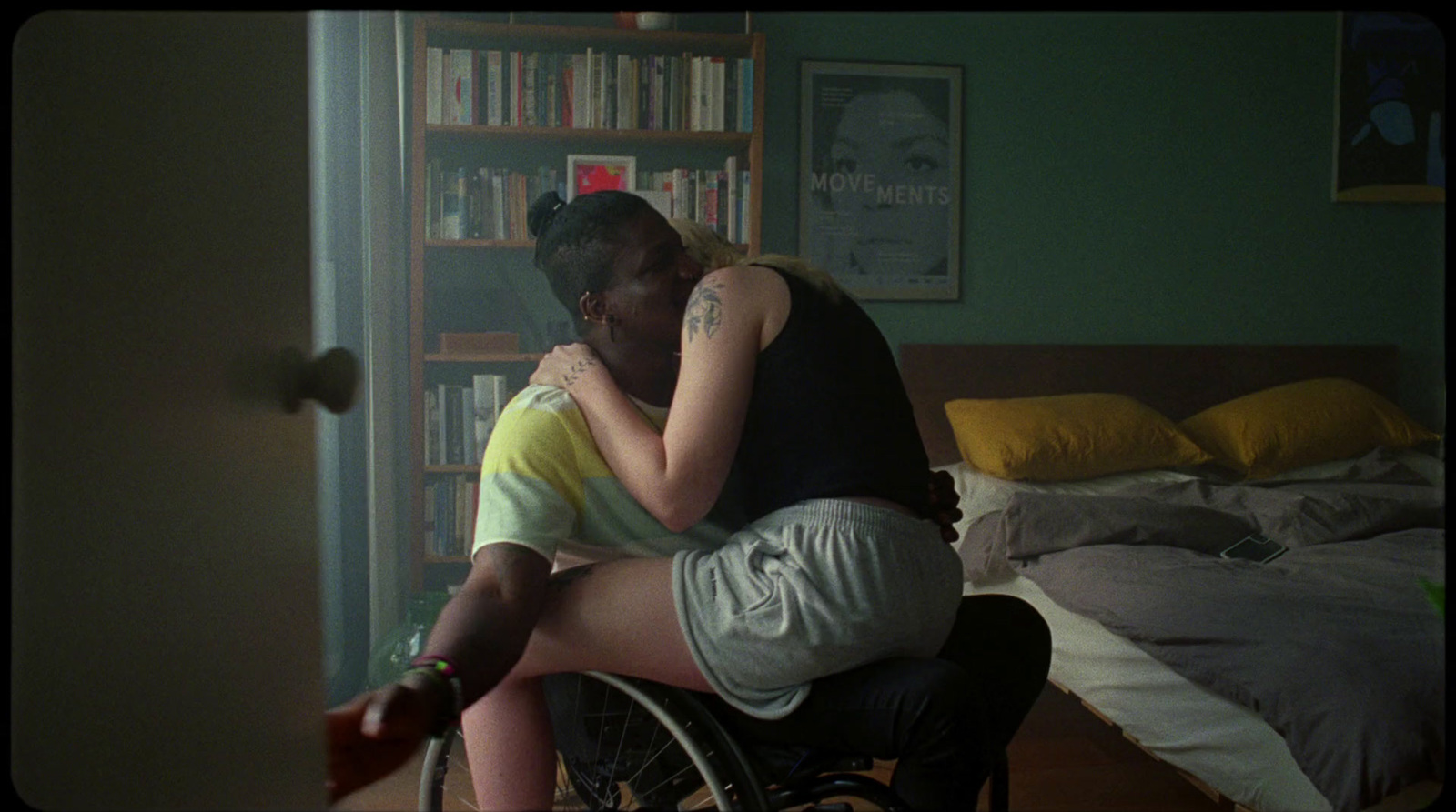 a man in a wheelchair hugs a woman in a bedroom