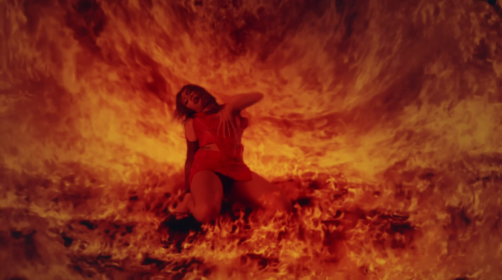 a woman in a red bodysuit sitting in front of a fire