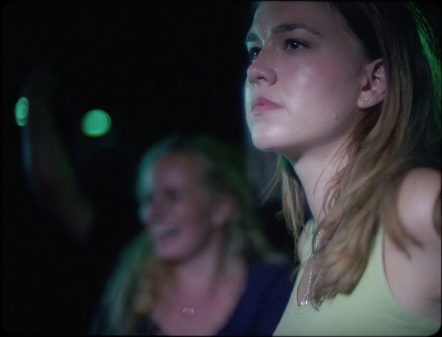 a woman standing next to another woman in a dark room