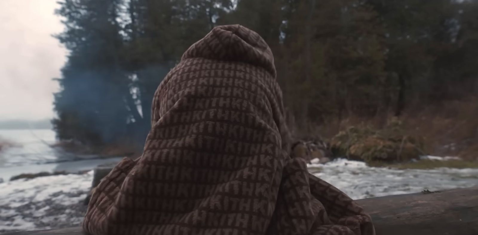 a person wrapped in a blanket looking out over a river