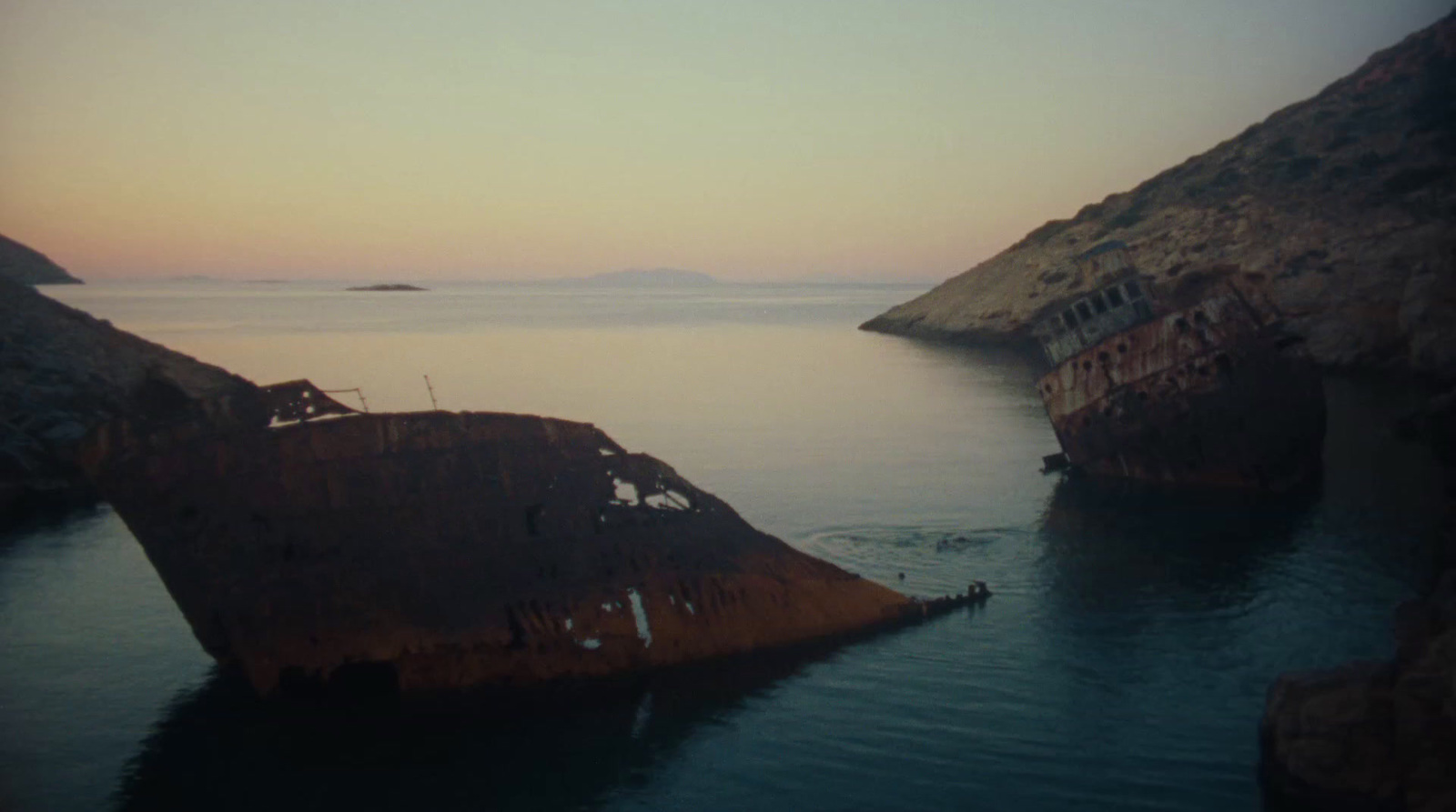 an old rusted ship sitting in the middle of a body of water