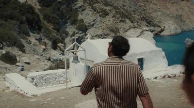 a man standing in front of a building next to a body of water