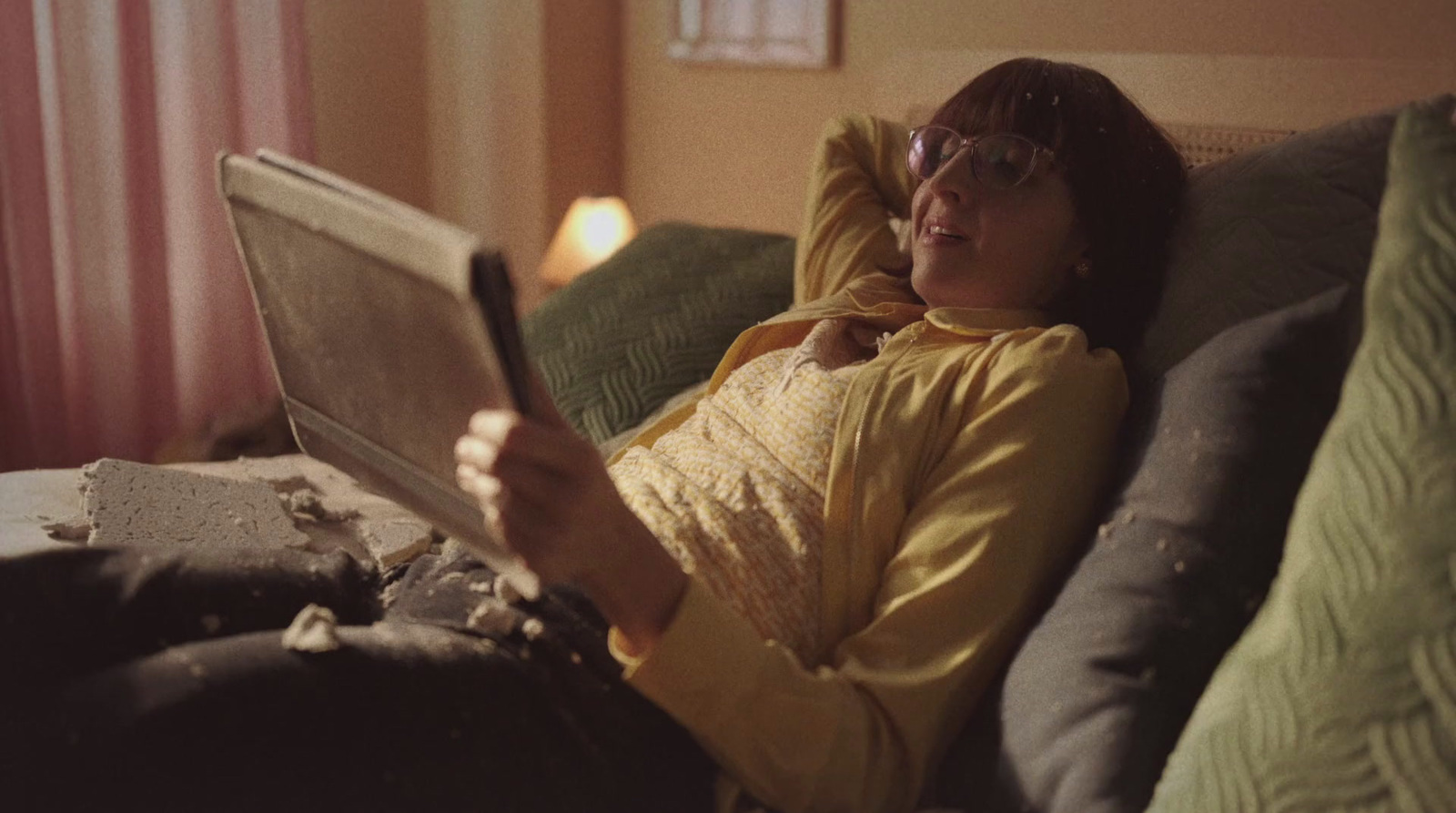 a woman laying on a couch reading a book