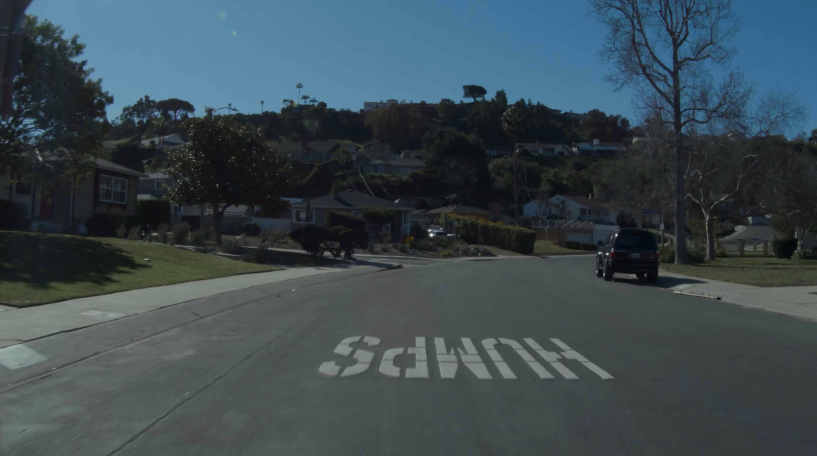 a car driving down a street next to a hill