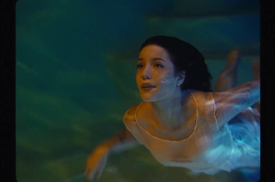 a woman in a white dress swimming in a pool