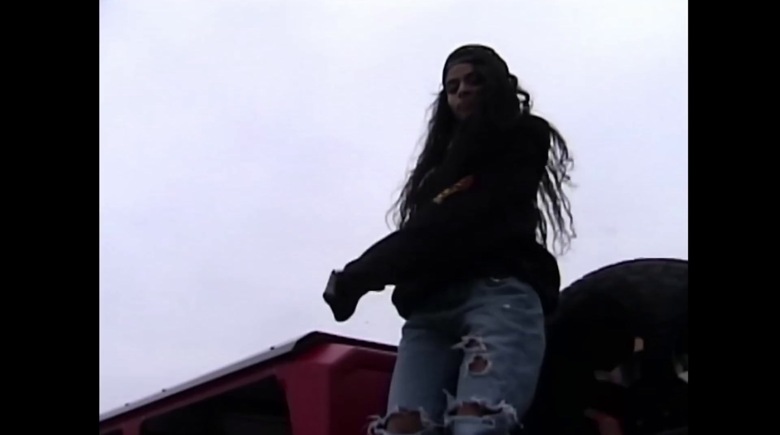 a woman with long hair standing on top of a truck