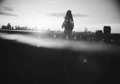 a black and white photo of a person standing on a roof