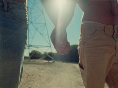 a couple holding hands while walking down a dirt road