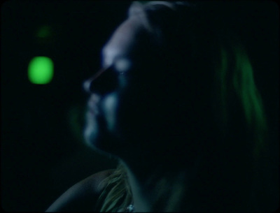 a woman in a dark room with a green light