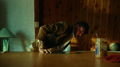 a man leaning over a table with a drink in front of him