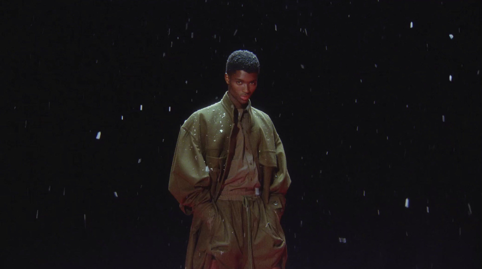 a man in a raincoat standing in the rain