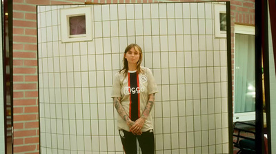 a woman standing in front of a tiled wall