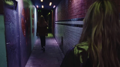 a woman walking down a dark alley way