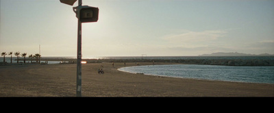 a view of a beach with people walking on it