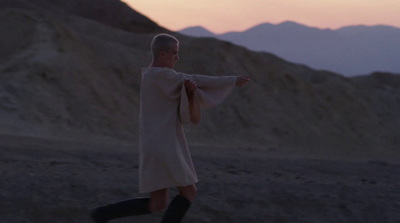 a man dressed in a robe is walking in the desert