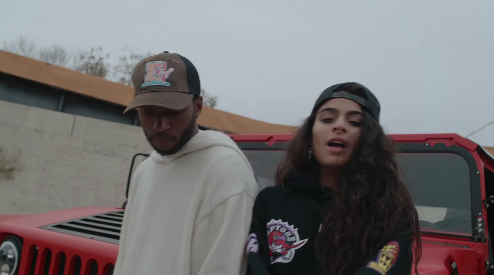 a man and a woman standing next to a red jeep