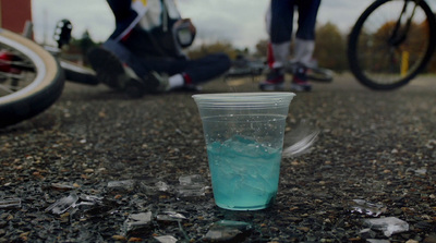 a cup filled with blue liquid sitting on the ground