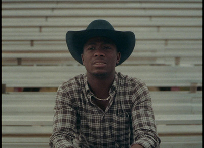 a man wearing a cowboy hat sitting on a bleachers