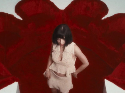 a woman standing in front of a large red flower