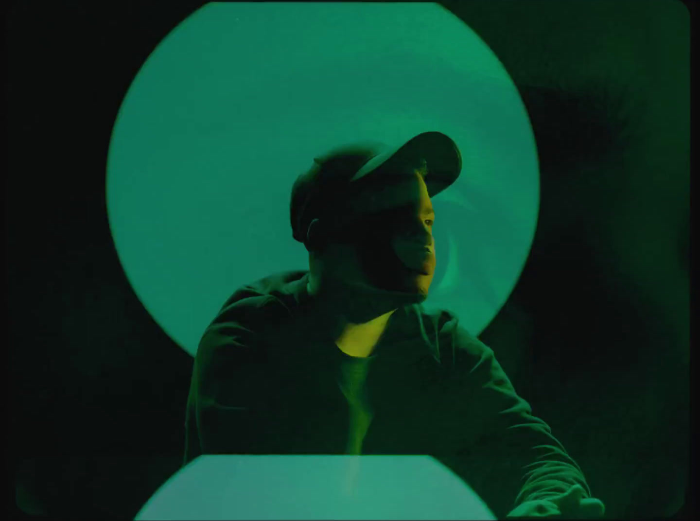 a man sitting at a table in front of a green light