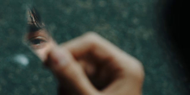 a person's hand holding a small object in front of a mirror