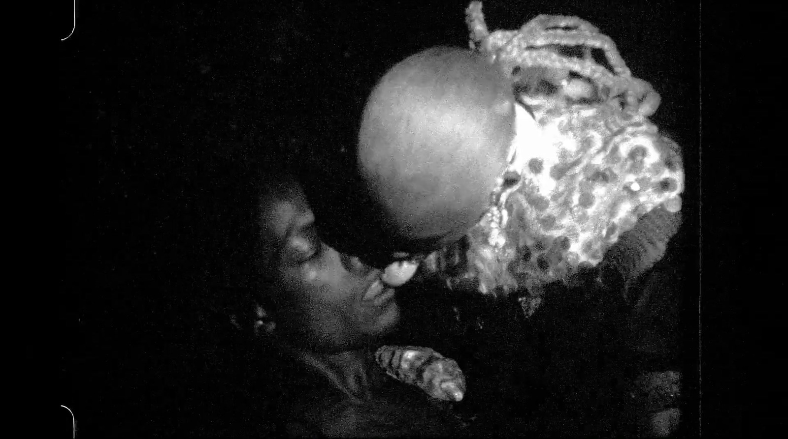 a black and white photo of a person kissing an apple