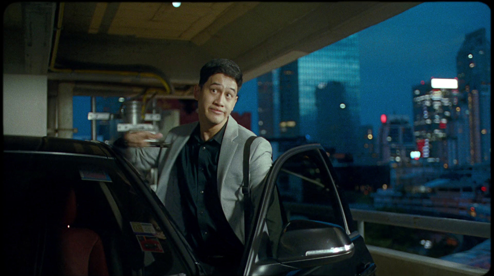 a man standing next to a car in a parking garage