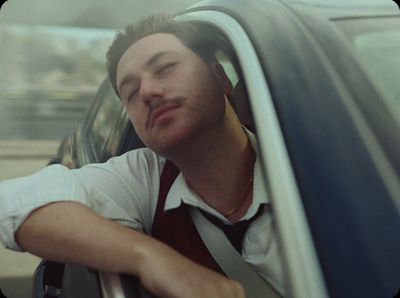 a man sitting in a car with his head out the window