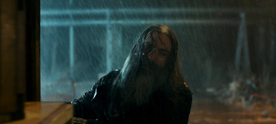 a man with long hair standing in the rain