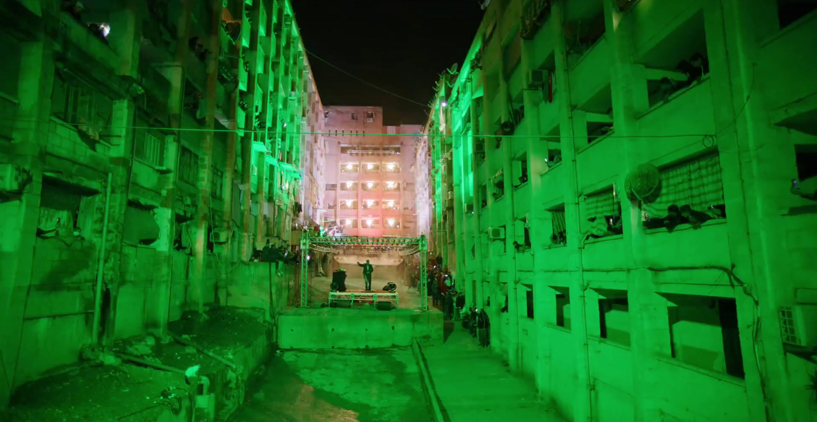 a narrow alley way with green lights on the buildings