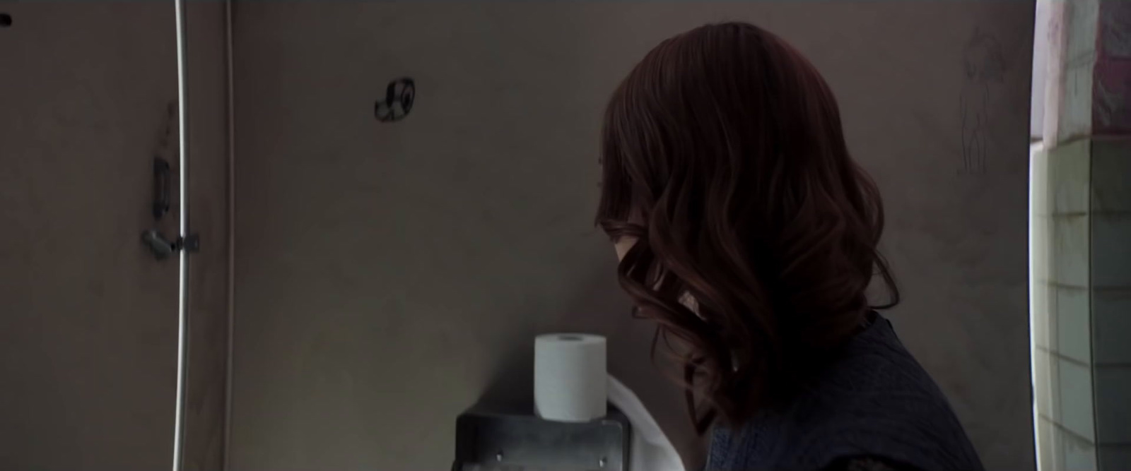 a woman standing in a bathroom next to a urinal