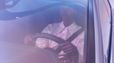 a man in a white shirt and tie driving a bus