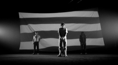 three people standing in front of a large flag