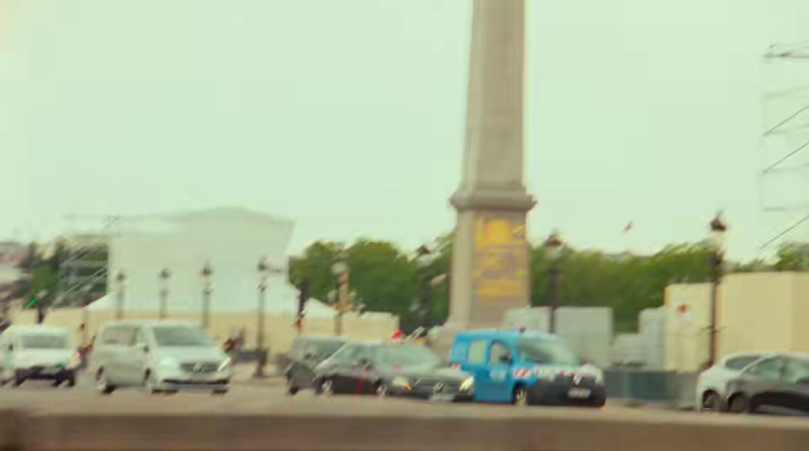 a blue truck driving down a street next to a tall clock tower