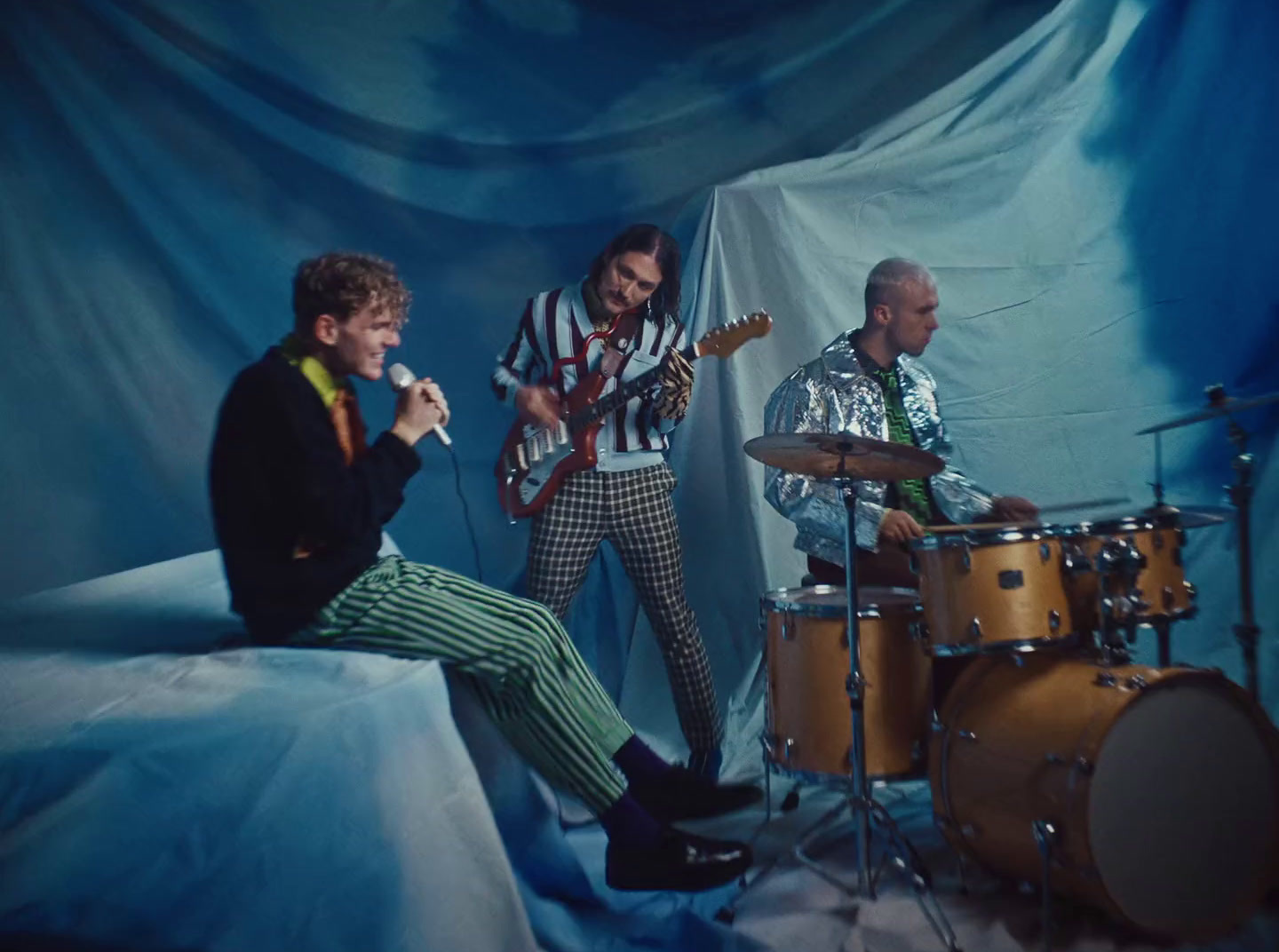 a group of men sitting around a drum set