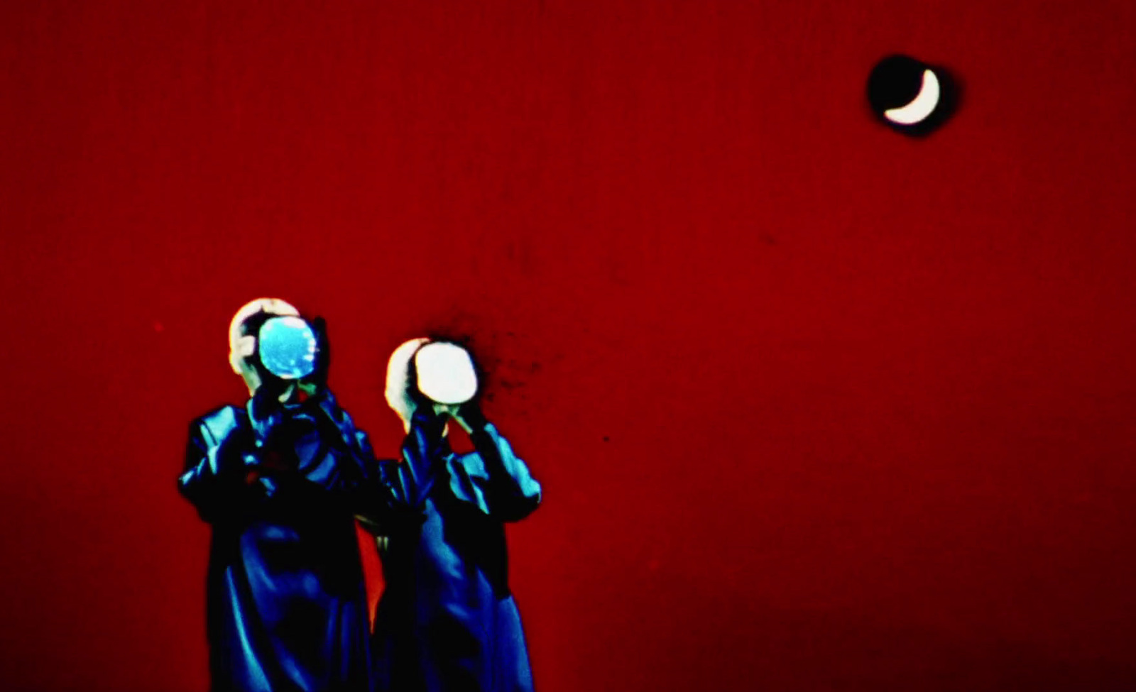 a couple of women standing next to each other in front of a red wall