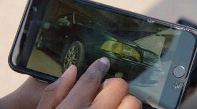 a person holding a cell phone with a car on the screen