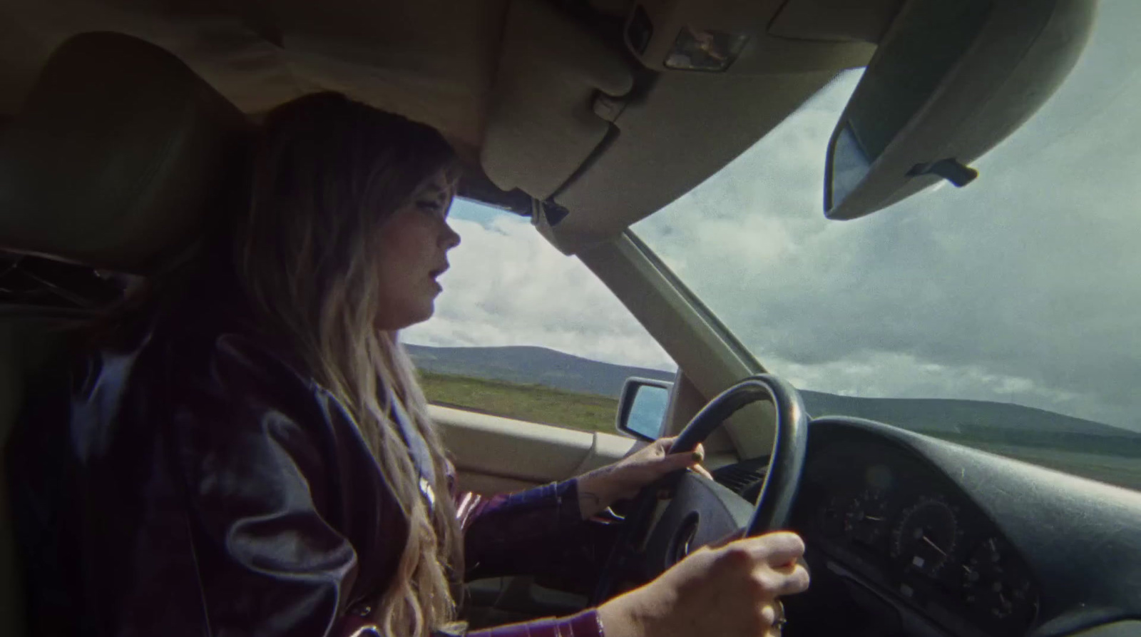 a woman driving a car on a cloudy day