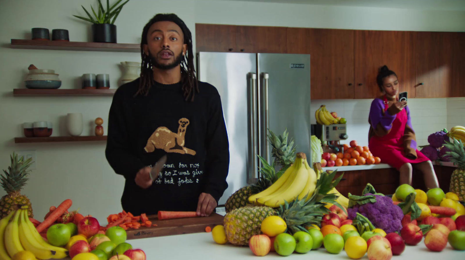 a man standing in a kitchen surrounded by fruits and vegetables