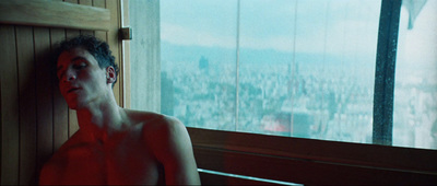 a shirtless man sitting in front of a window