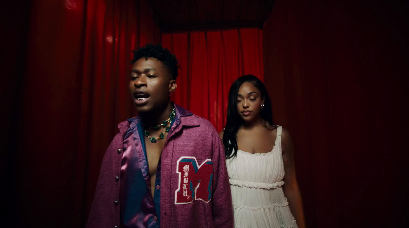 a man and a woman standing in front of a red curtain