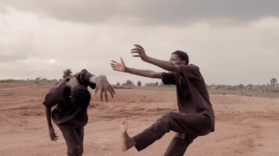 two men playing with a frisbee on a dirt field