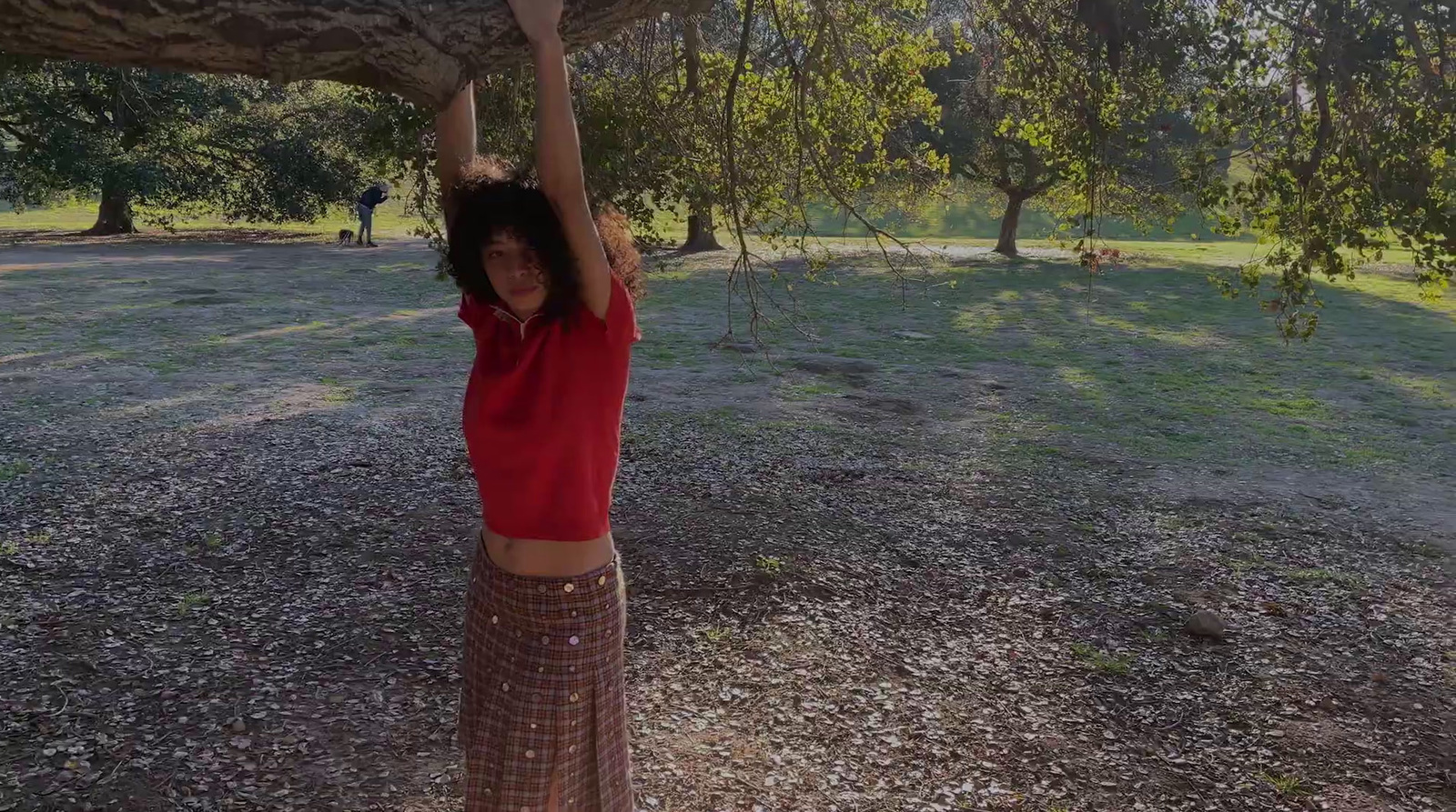 a woman in a red shirt is holding a tree branch