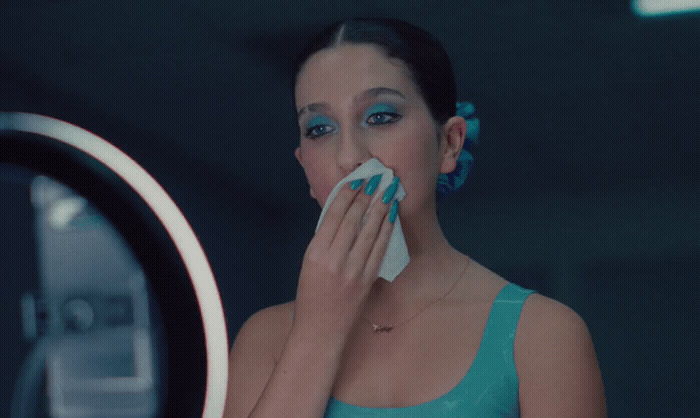 a woman with blue eyes is blowing her nose