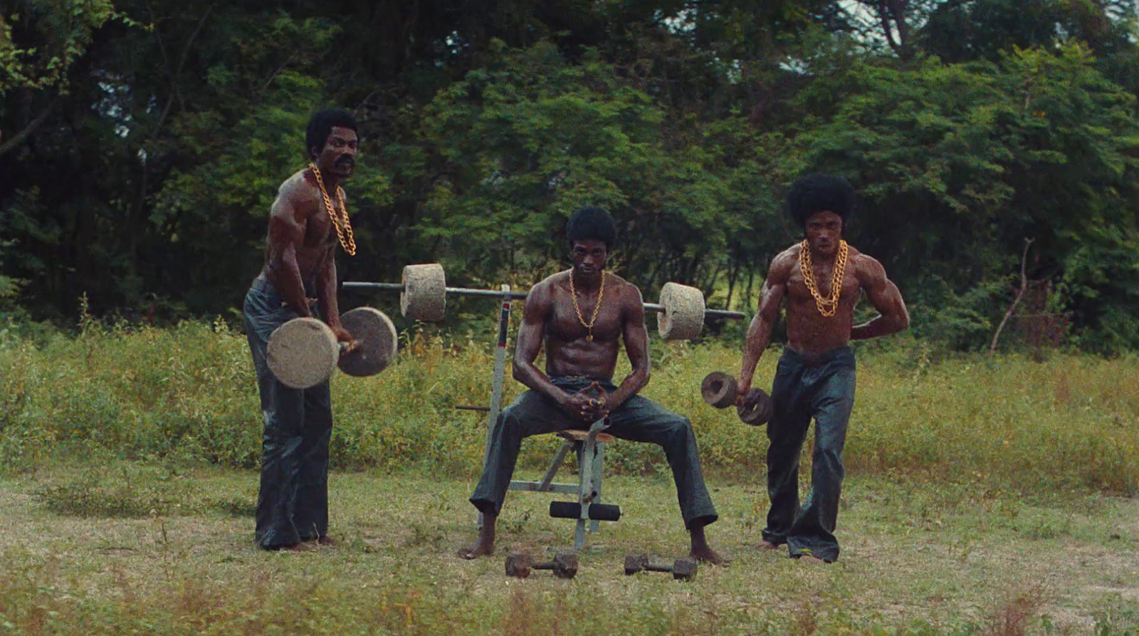 a group of three men standing next to each other in a field