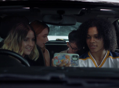 a group of people sitting in a car looking at a cell phone