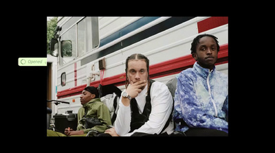 two men sitting next to each other in front of a bus